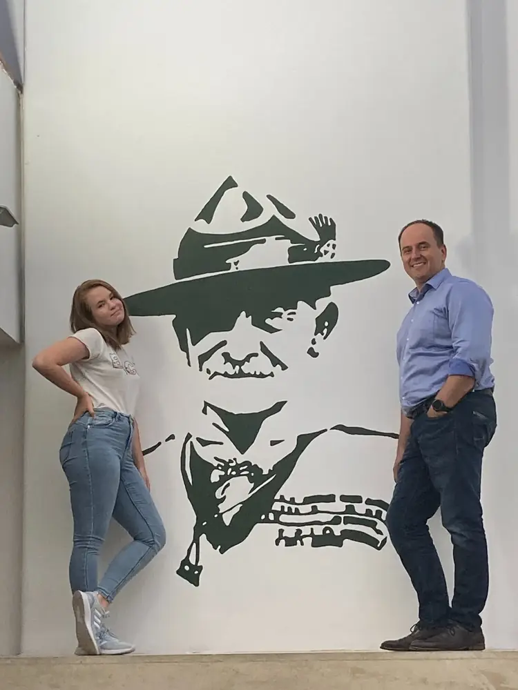 Két ember a falra festett Baden-Powell-portré mellett