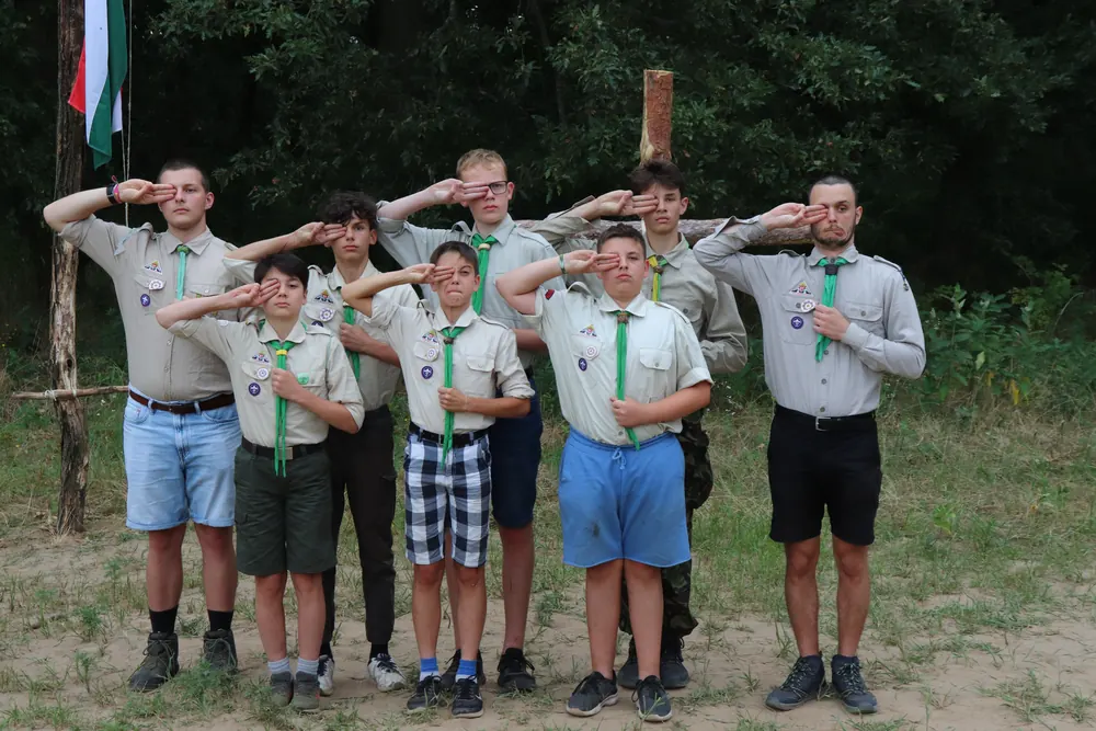 Cserkészek tisztelegnek sorban egy zászló előtt