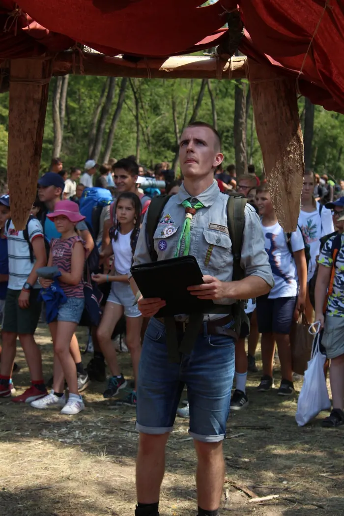 Egy vezető áll a tábori gyülekezőn, körülötte gyerekek